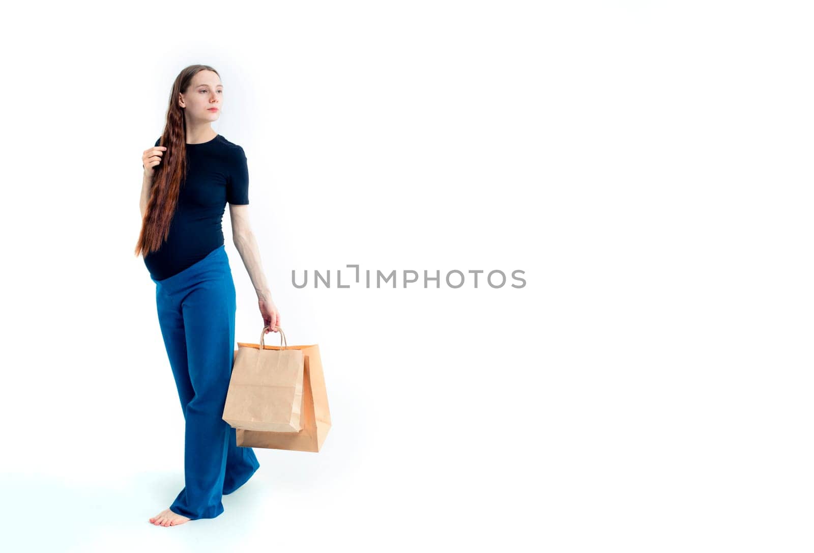 Shopping concept: Young pregnant woman with shopping bags full length portrait on white background.