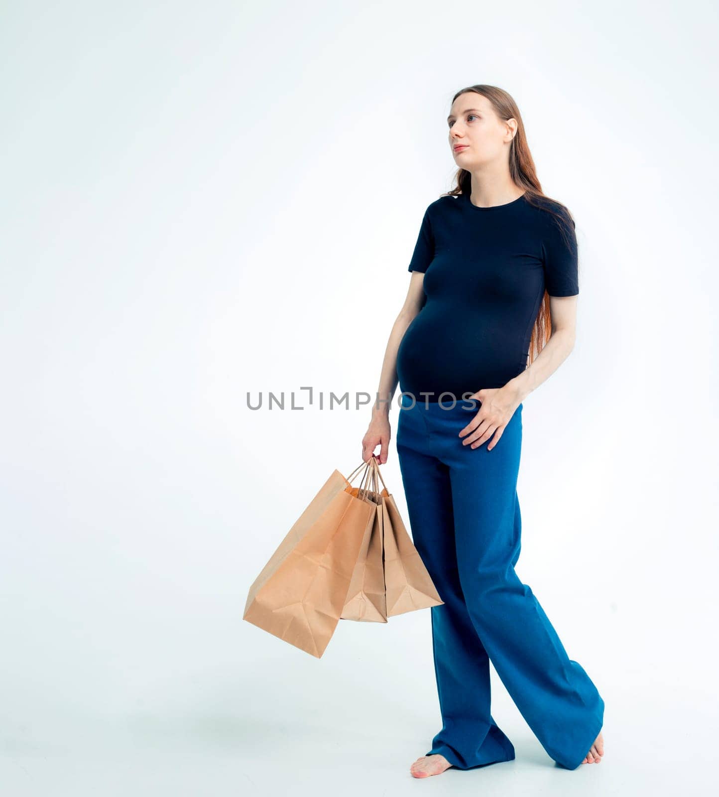 Shopping concept: Young pregnant woman with shopping bags full length portrait on white background.