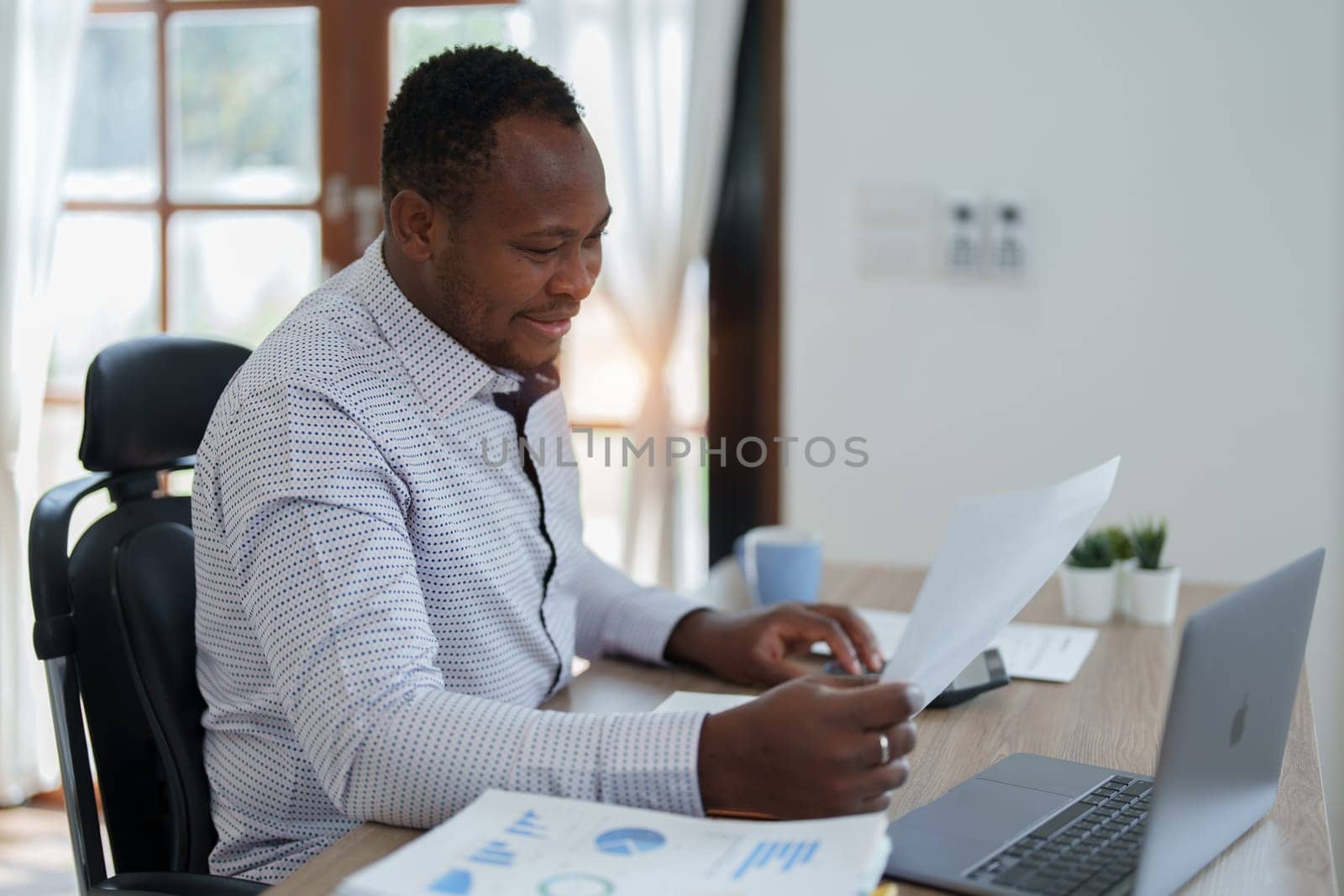middle aged man American African using computer laptop with planning working on financial document, tax, exchange, accounting and Financial advisor by Manastrong