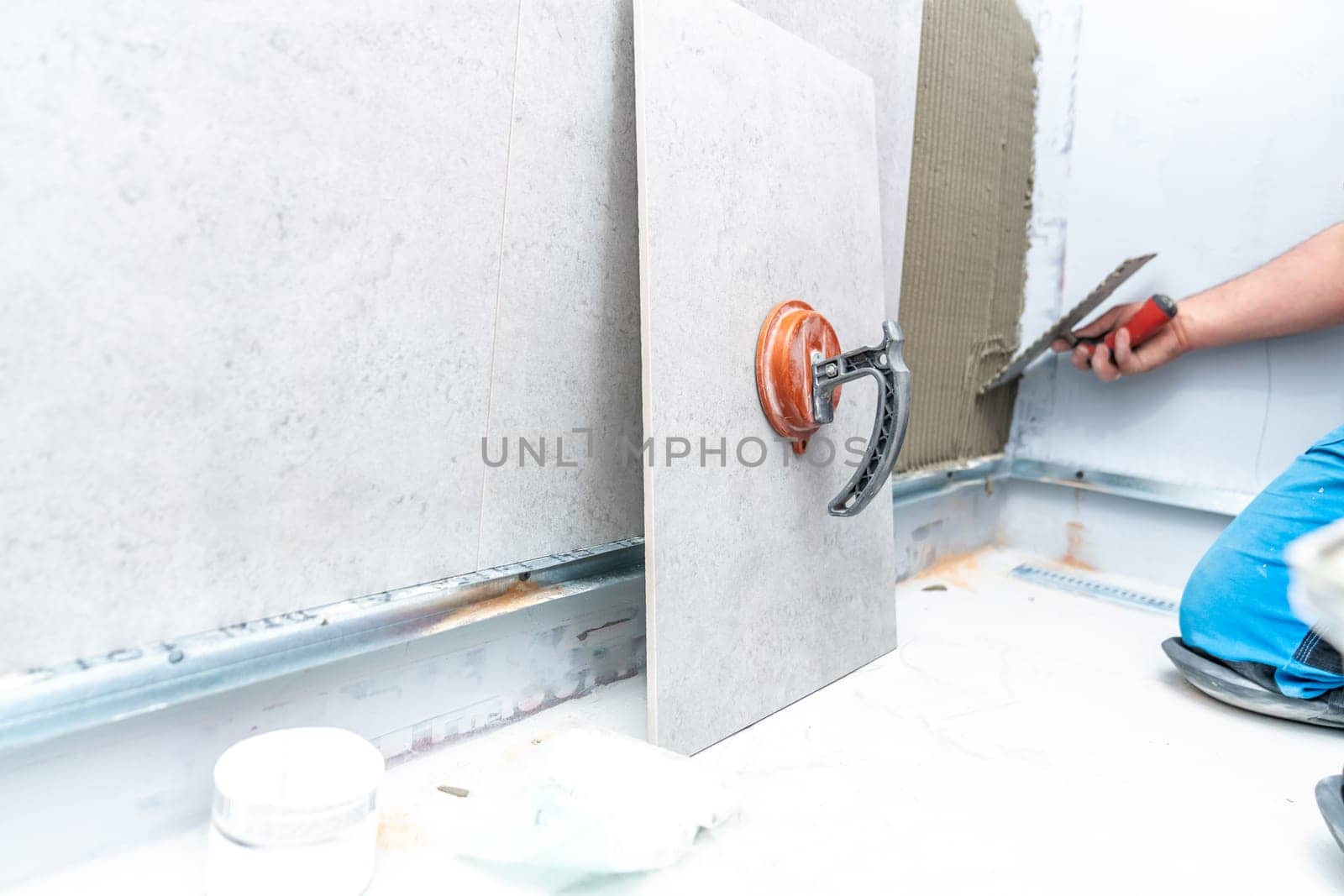 craftsman tiling the room with large format tiling. High quality photo