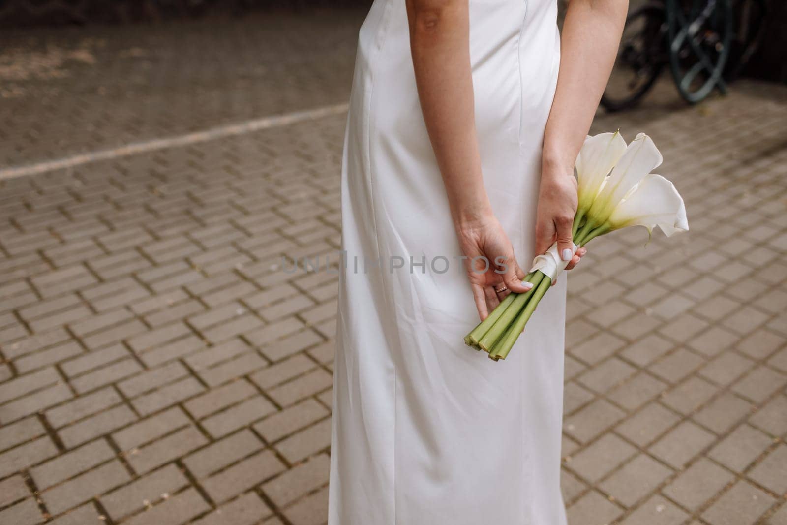 Bridal bouquet. Wedding. The slim woman in a white dress holds a beautiful bouquet of white flowers outdoors.
