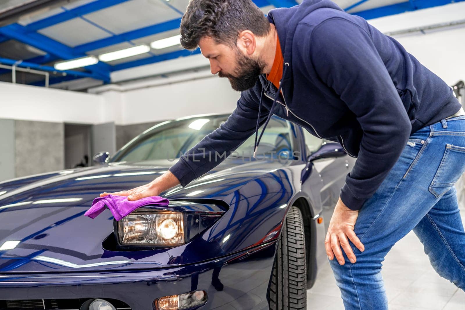 detailing and polishing the body of a luxury sports car using a microwipe. High quality photo