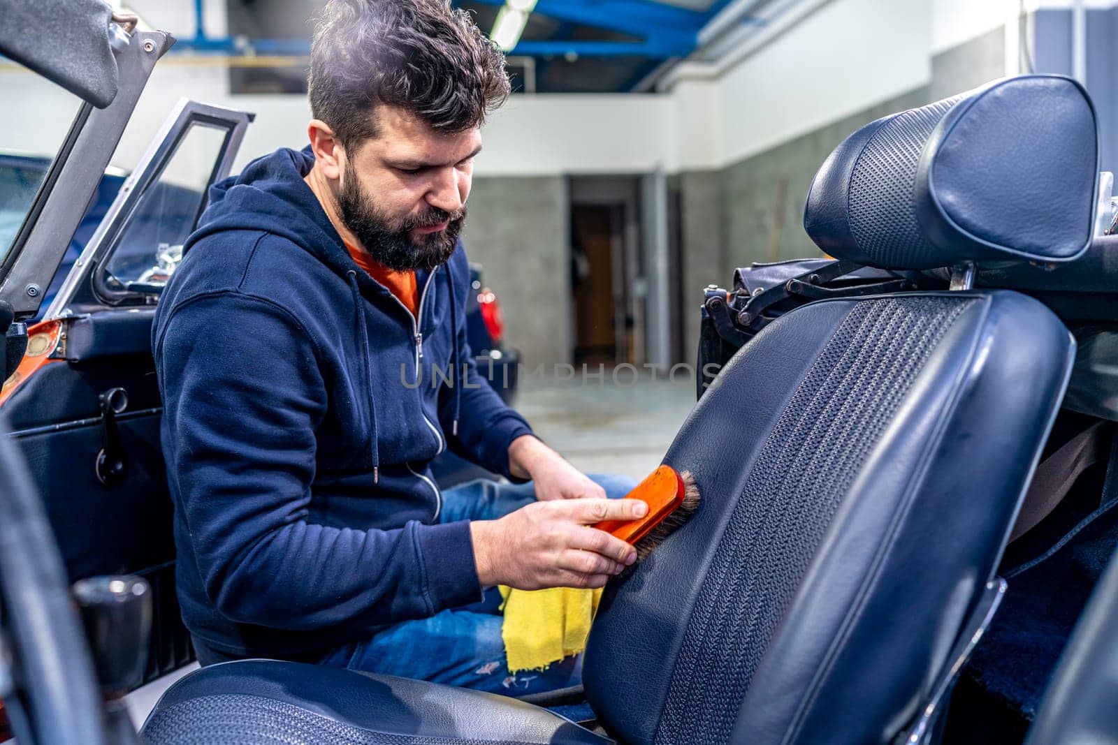 cleaning leather car seats with a brush and chemicals.