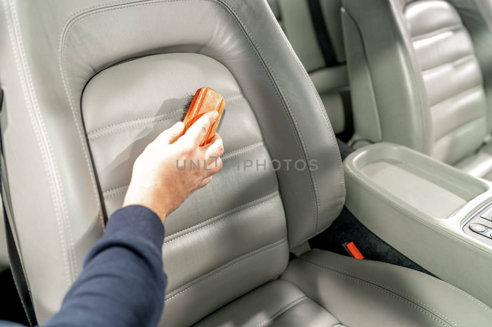 cleaning leather car seats with a brush and chemicals.