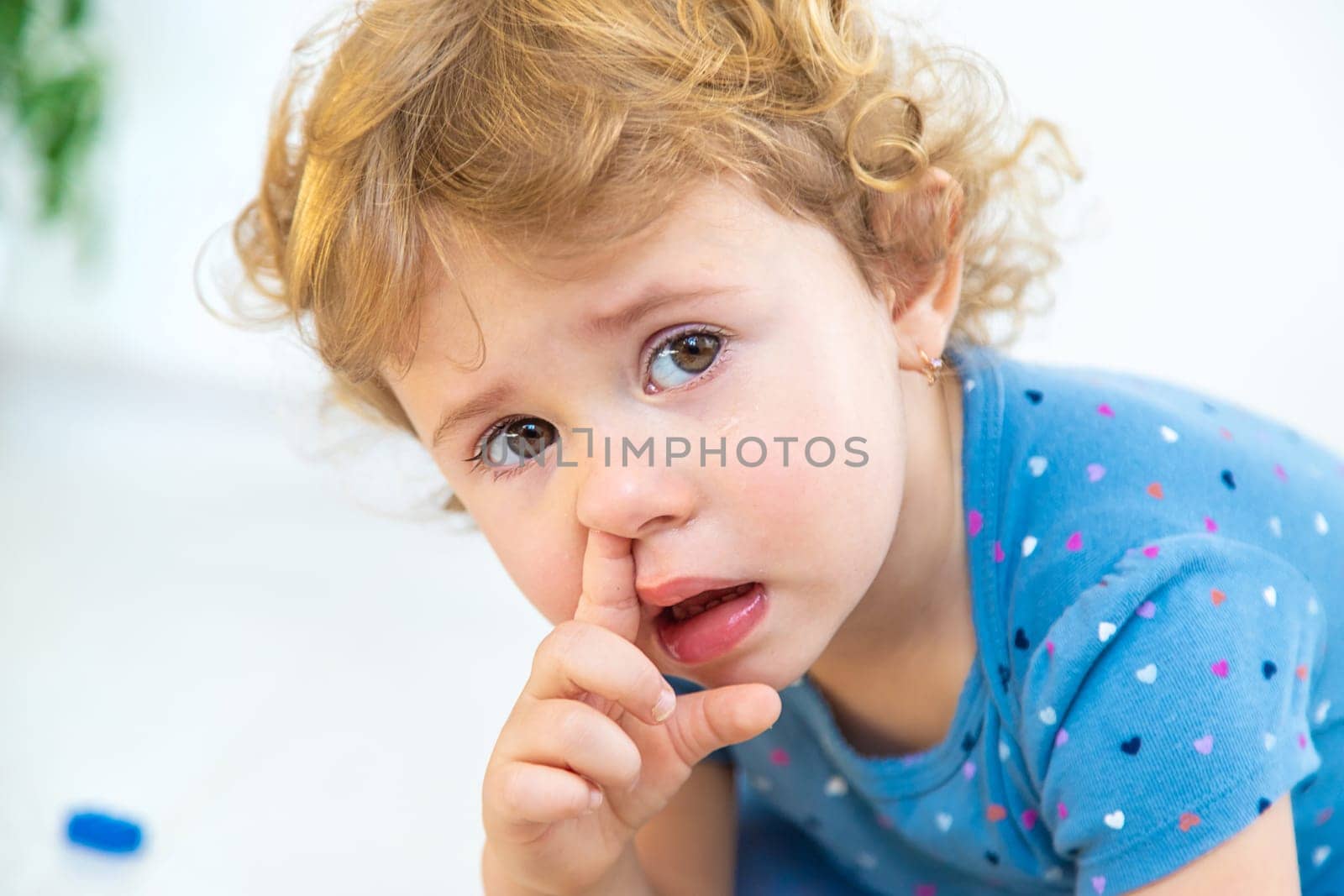 The child sticks his finger in his nose. Selective focus. Kid.