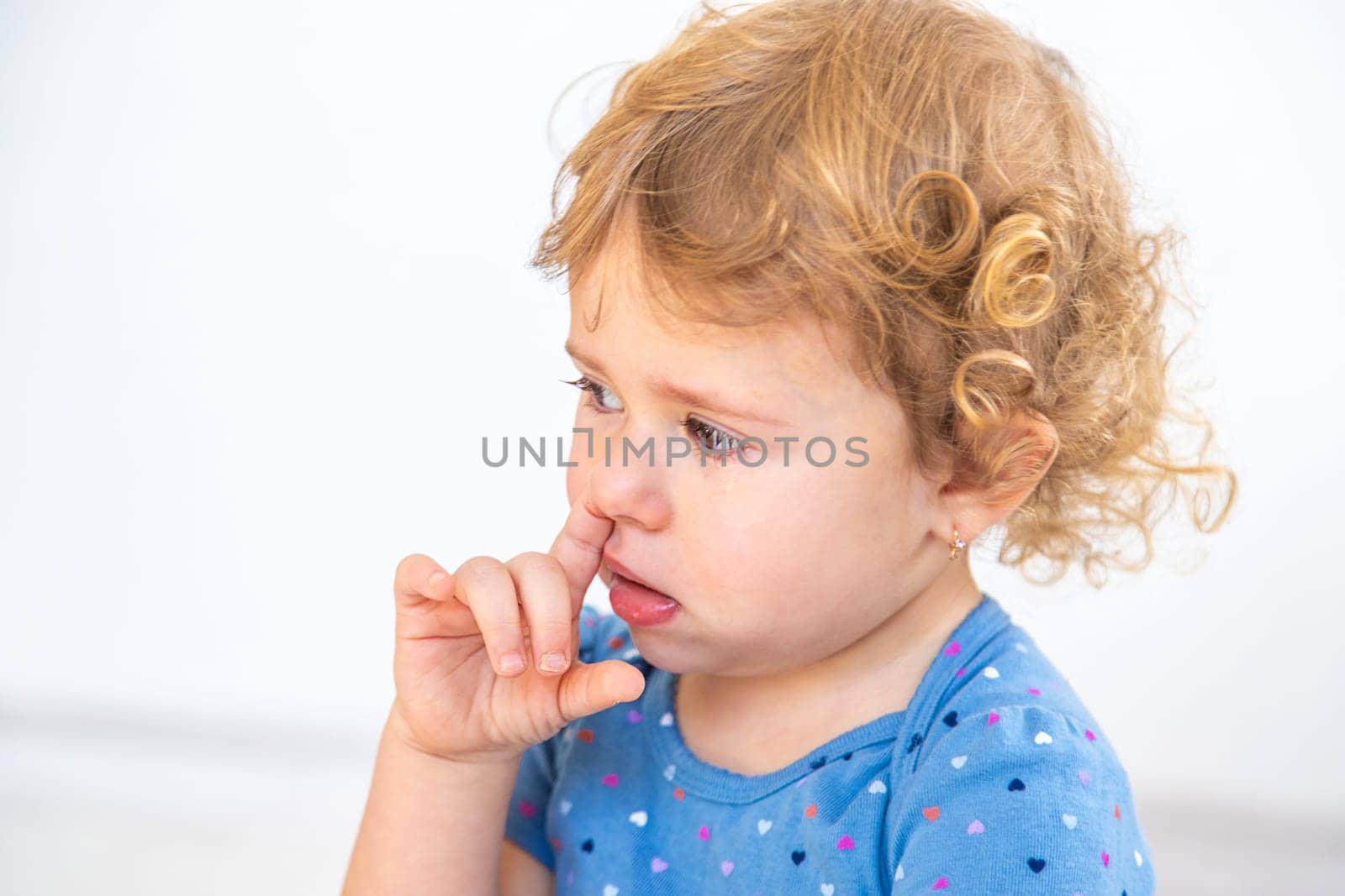 The child sticks his finger in his nose. Selective focus. by yanadjana