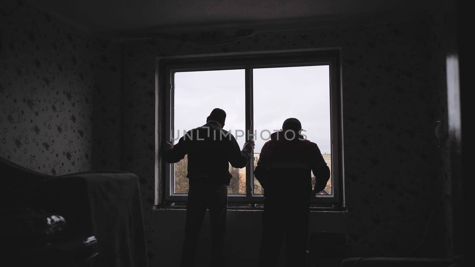 Silhouettes of workers installing new plastic windows