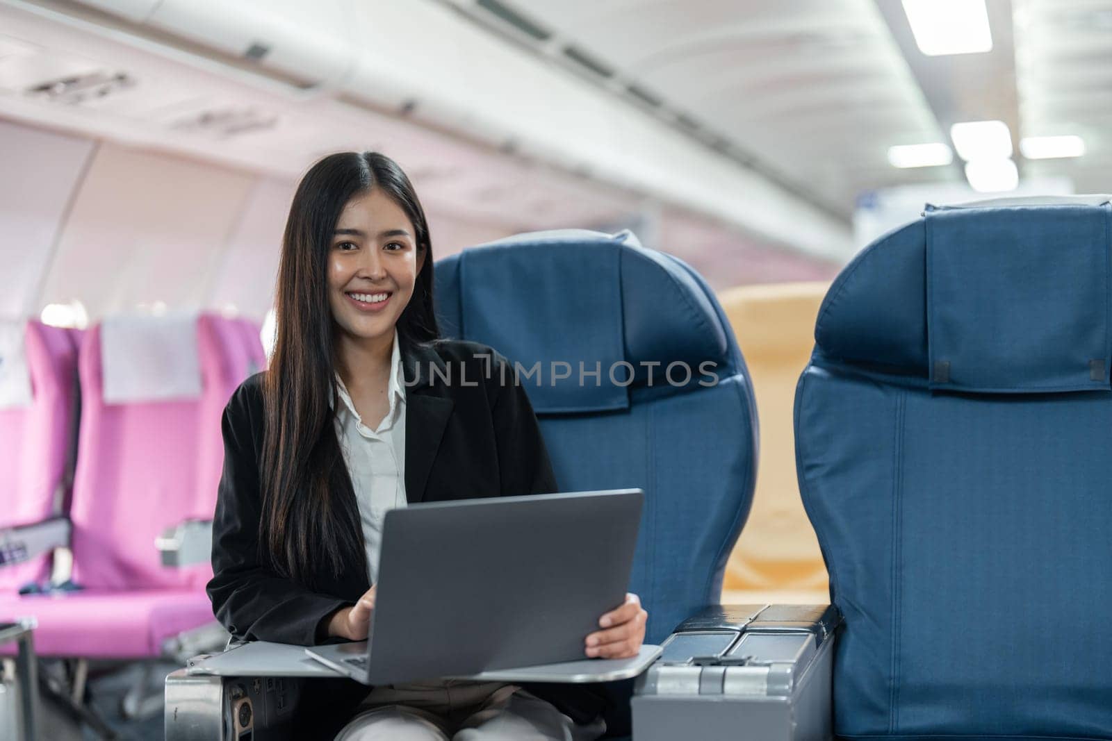 Female passenger sitting on plane while working on laptop computer with simulated space using on board wireless connection by nateemee