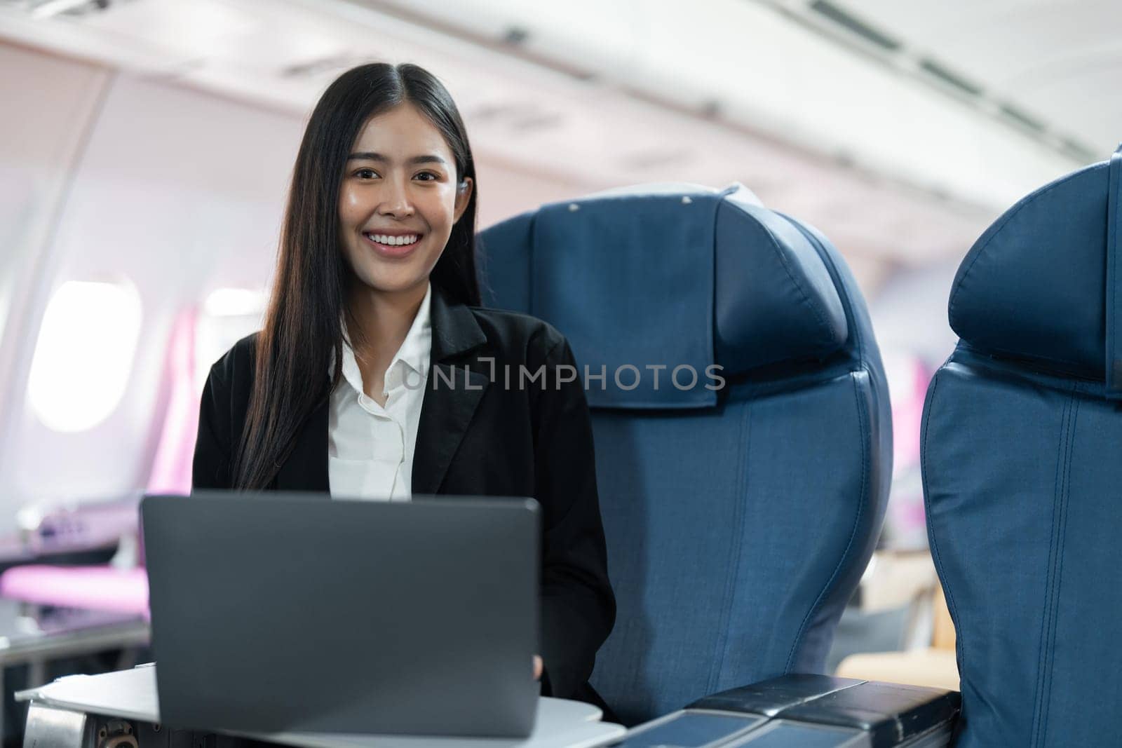 Female passenger sitting on plane while working on laptop computer with simulated space using on board wireless connection by nateemee