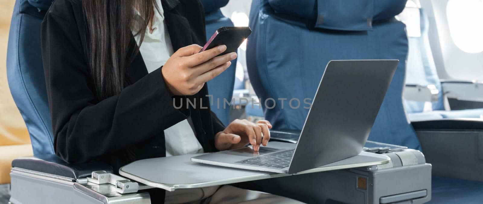 transport, tourism and technology concept - close up of business woman with smartphone and laptop traveling by plane.