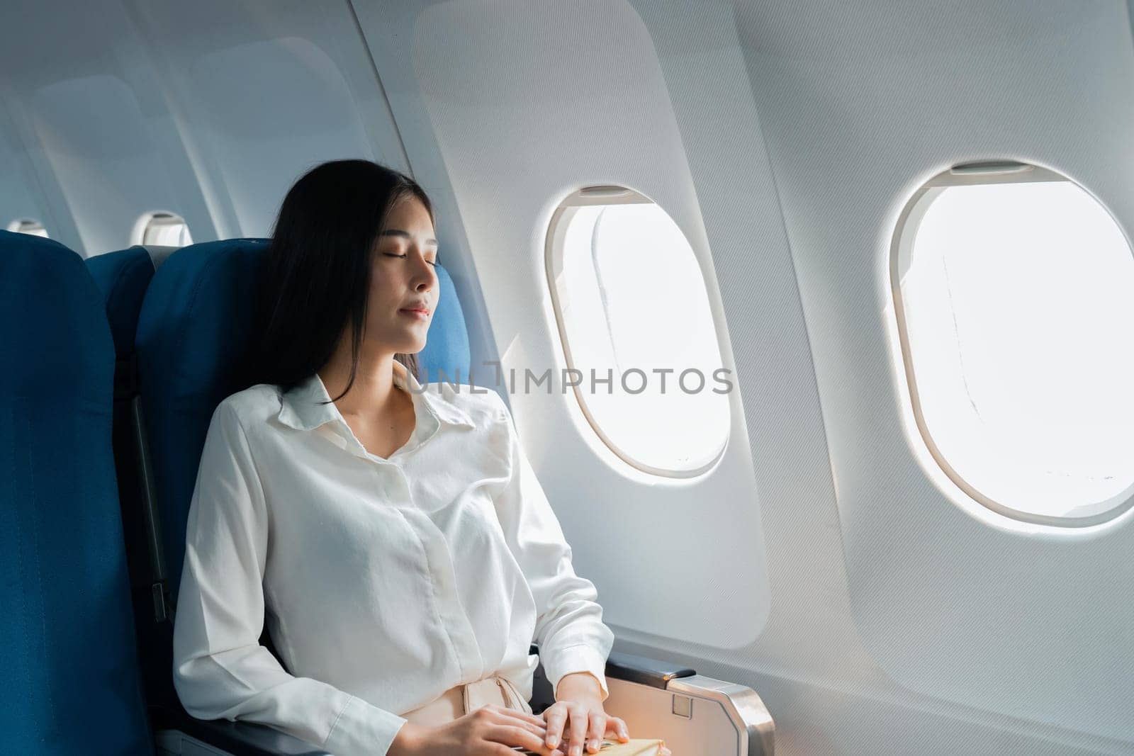 A female passenger traveling by plane sleeping on cushion airplane.