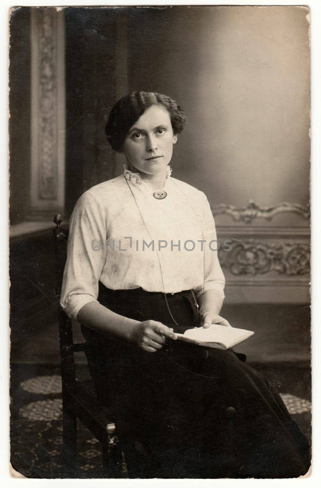 GERMANY - CIRCA 1920s: Vintage photo shows a young woman. She wears Edwardian hairstyle. Retro black and white studio photography with sepia effect. Circa 1950s.