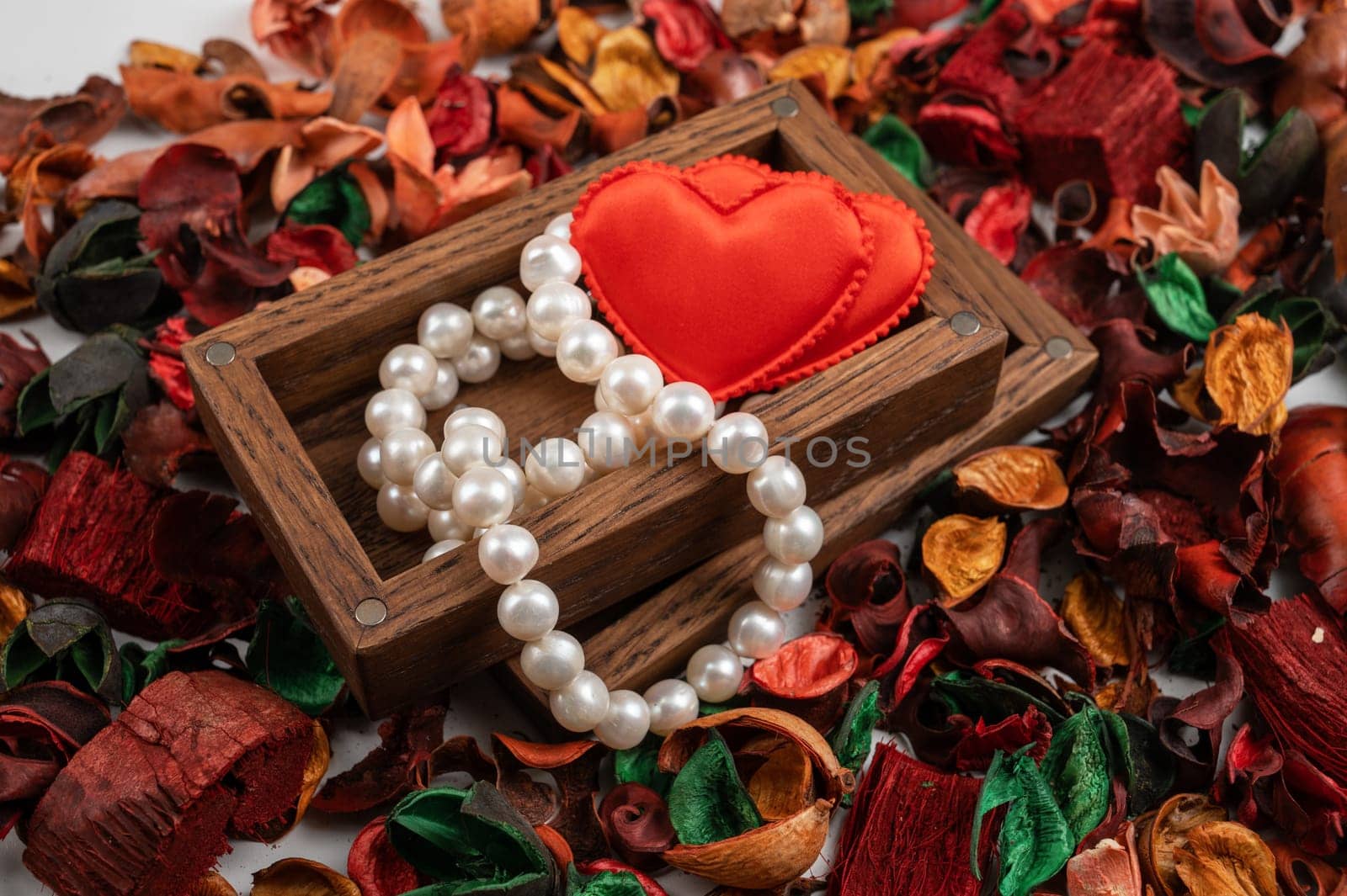 Pearl jewelry with red hearts in wooden box on dry flowers background. Valentines day gift concept