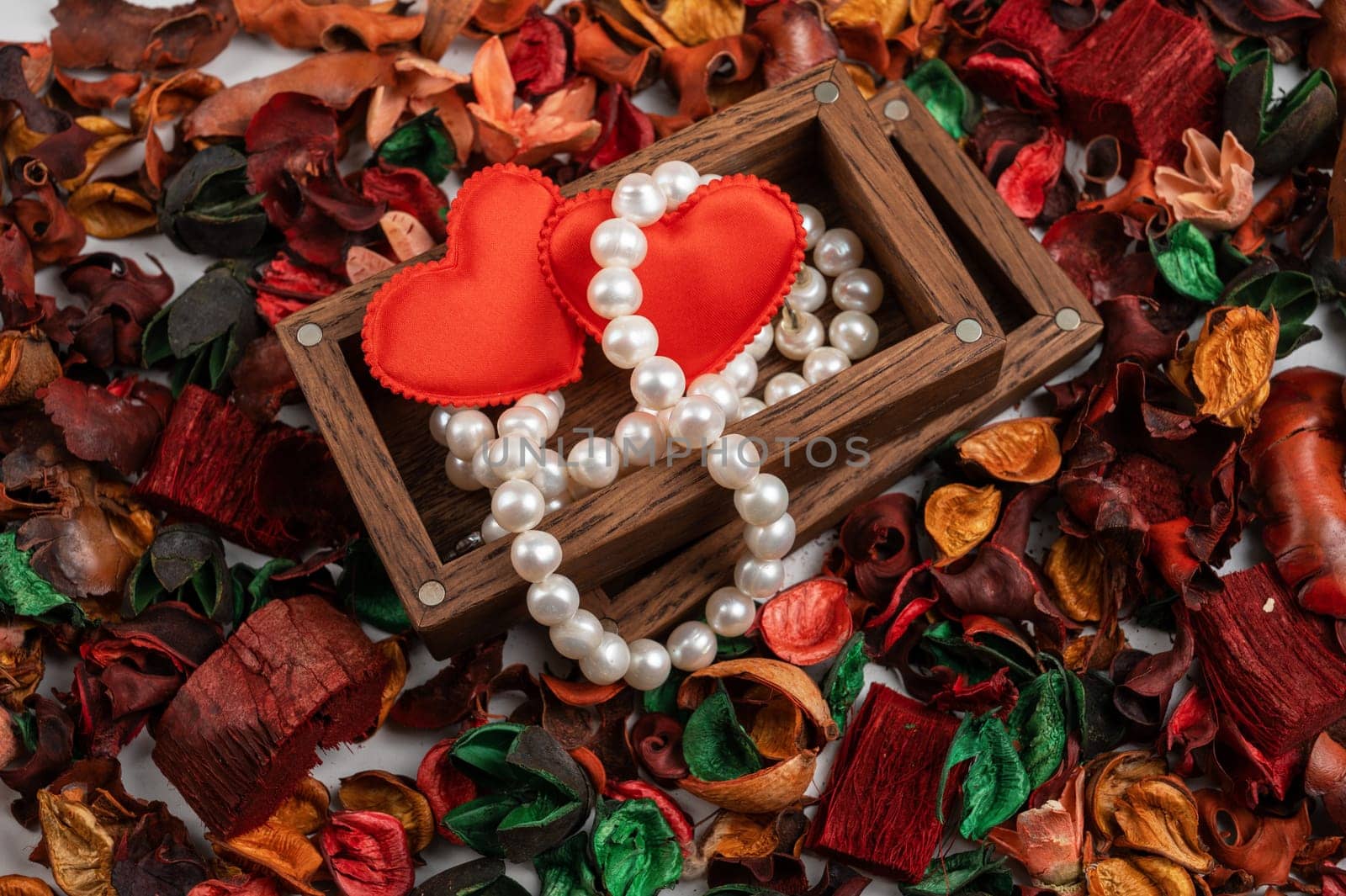 Pearl jewelry with red hearts in wooden box on dry flowers background. Valentines day gift concept