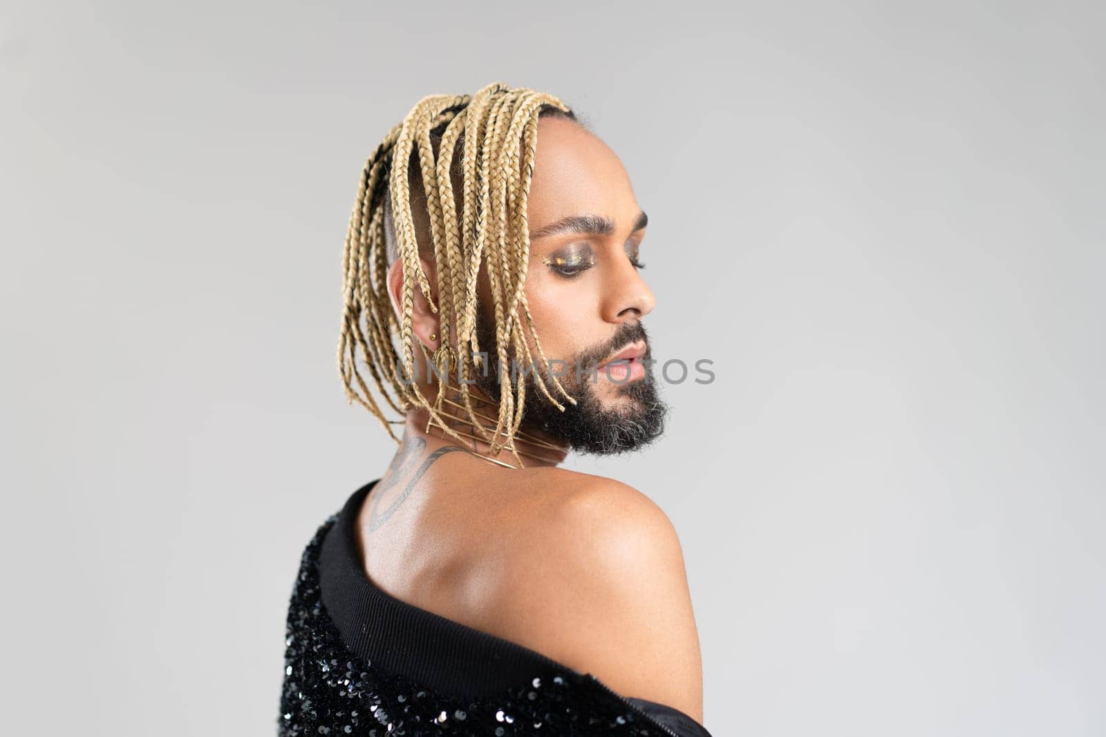 Afro-american homosexual male posing in photo studio on white background. Bearded gay with beard and make up close up portrait