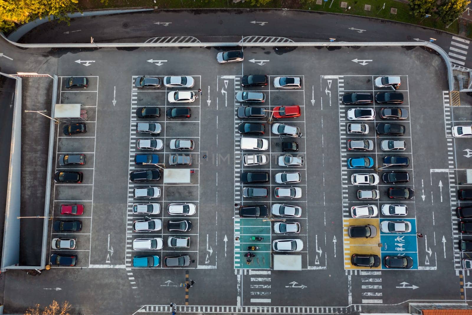 Aerial view of large car parking with many parked cars. Car park near shopping mall with lines and markings for vehicle places and directions