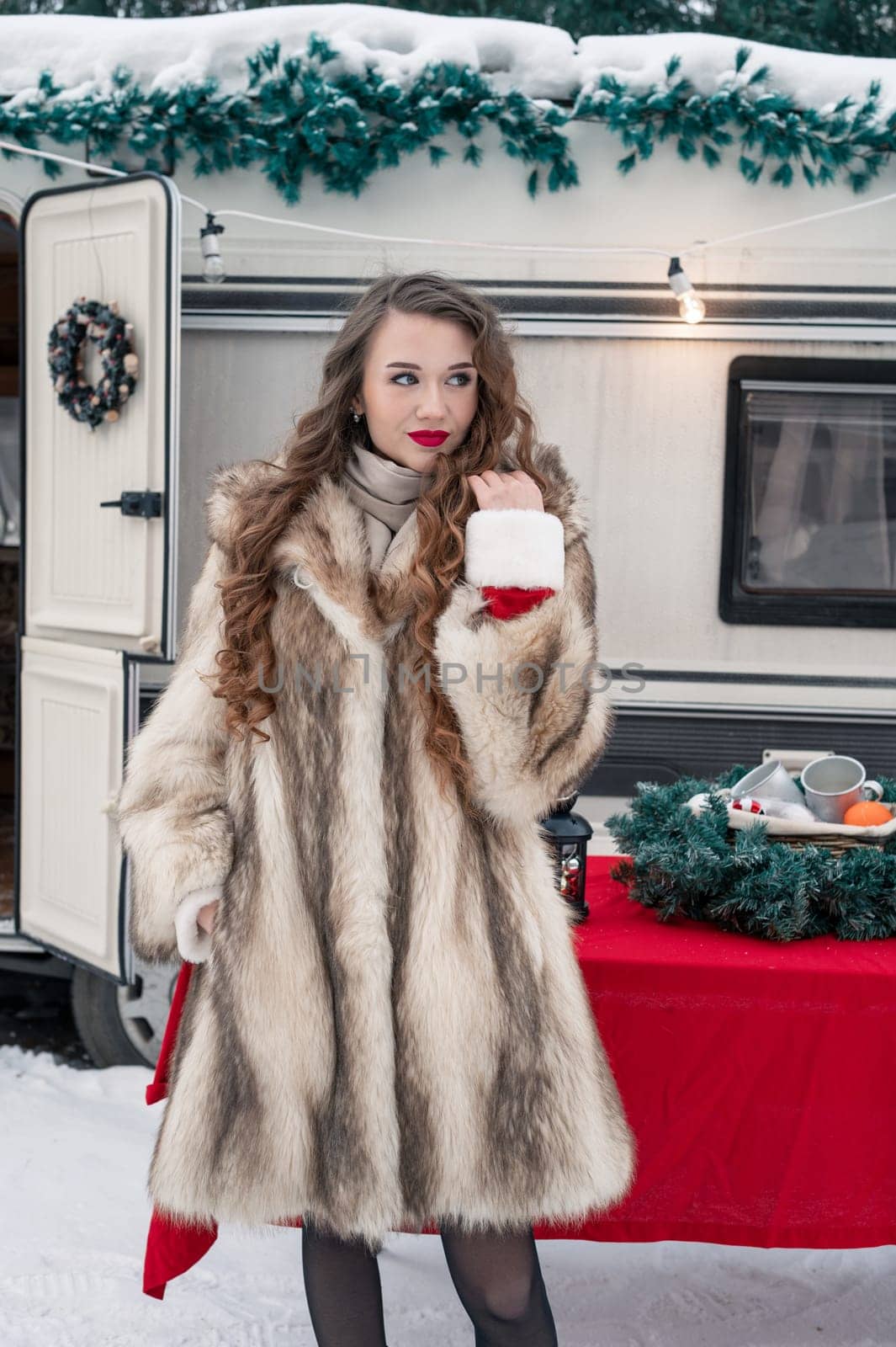 Young woman in fur coat with gift box at winter campsite getting ready for the new year.