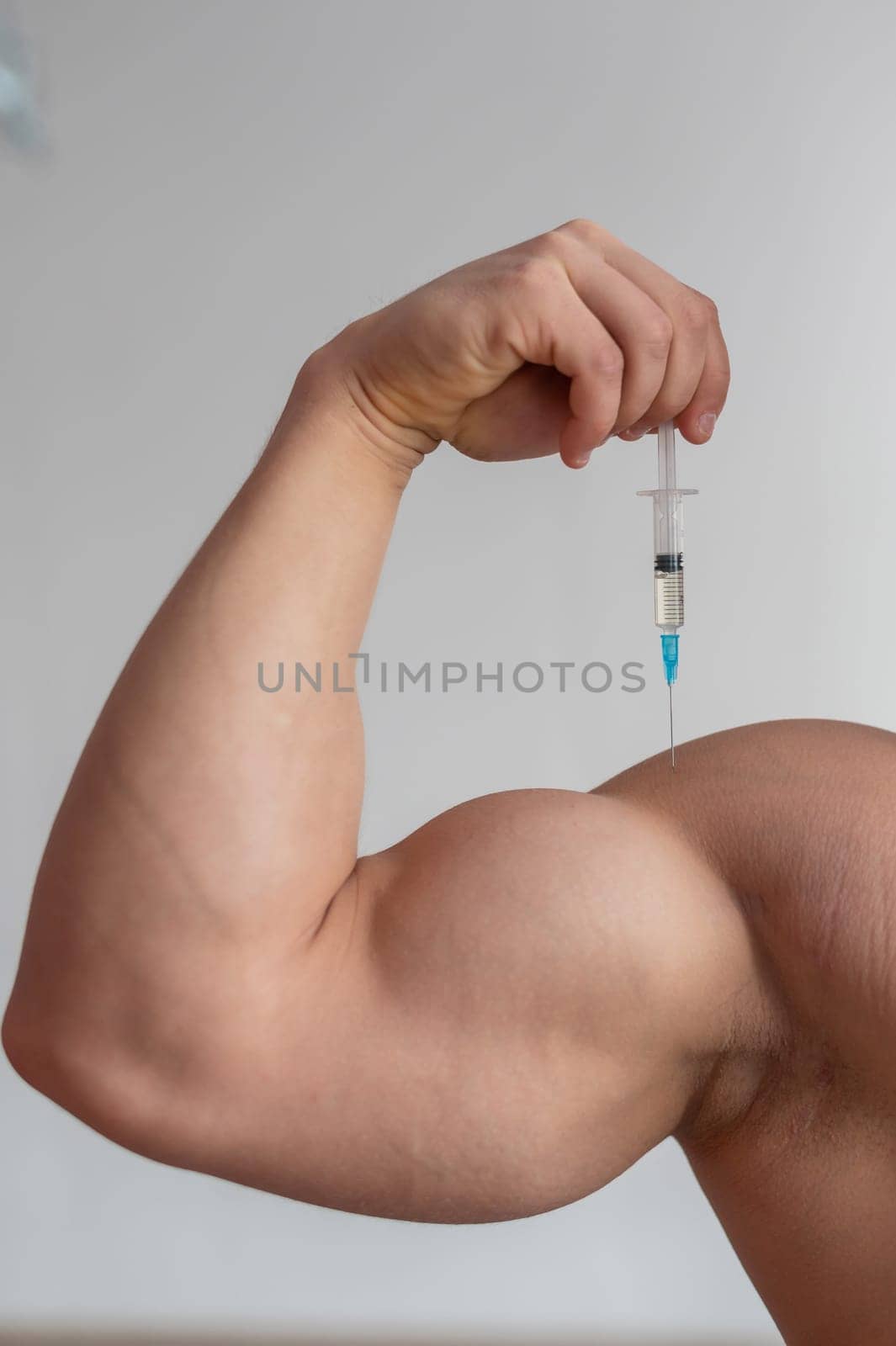 Close-up of male biceps. Unrecognizable male bodybuilder puts himself an injection of testosterone. Faceless athlete takes growth hormone. Vertical
