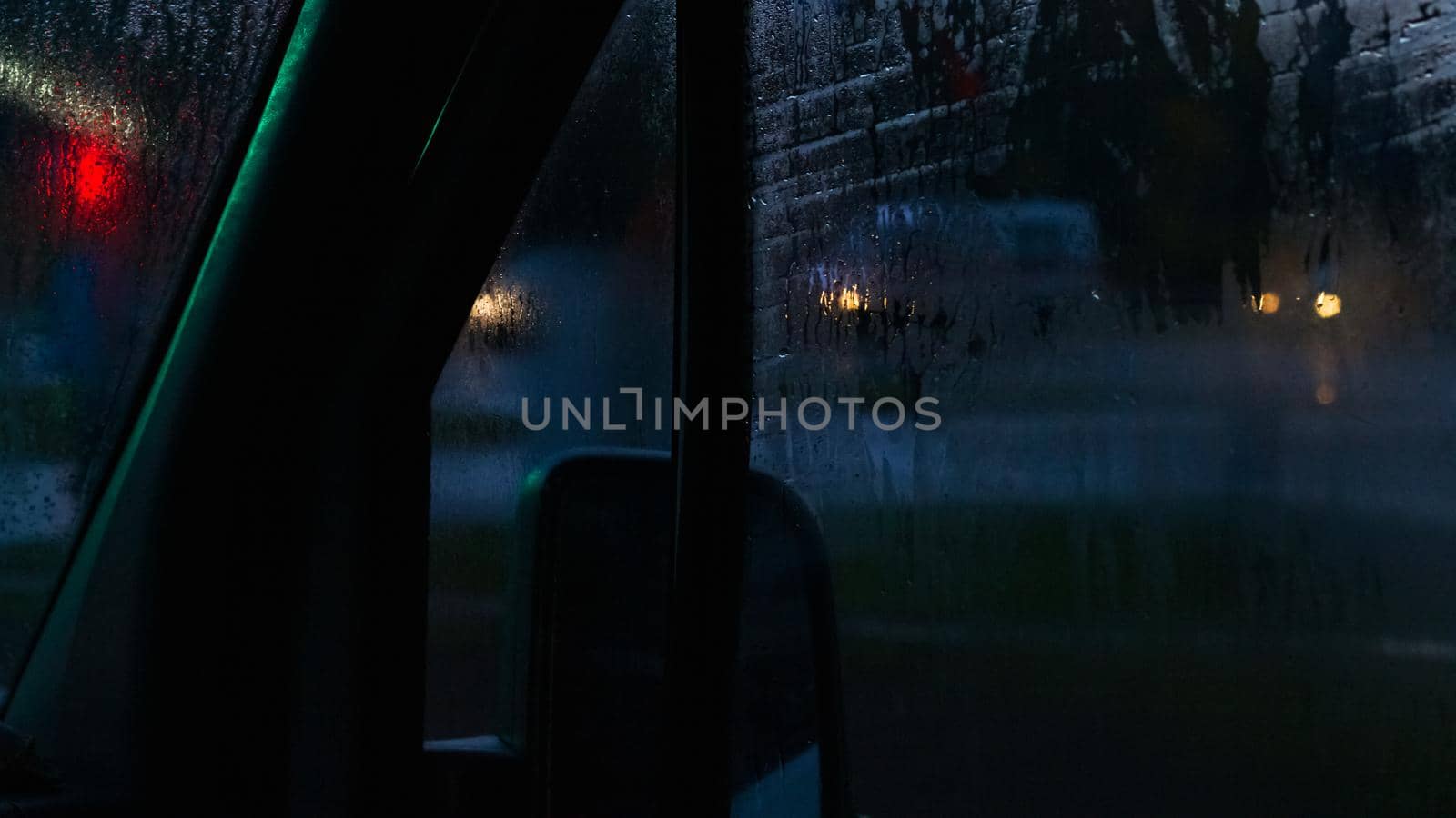 Side window of a car at night with raindrops close up