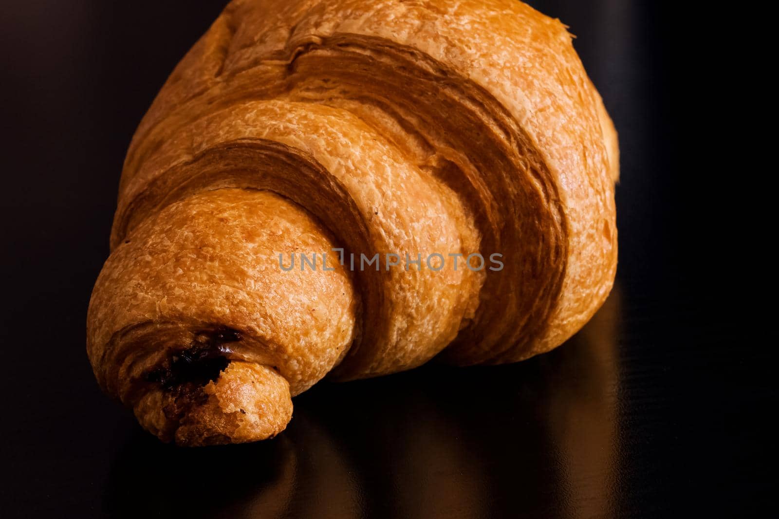 Croissant with chocolate on a black wooden table
