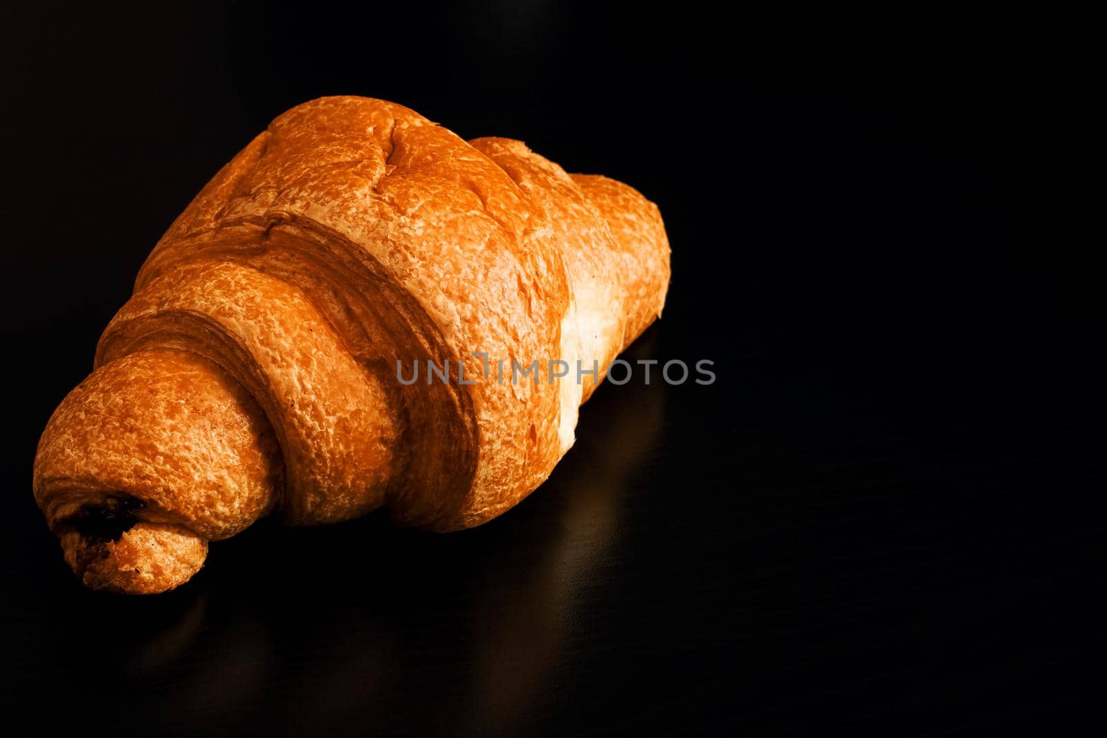 Croissant with chocolate on a black wooden table, copy space