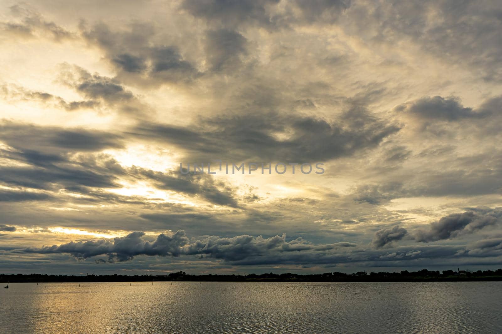 The clouds filled the sky, obscuring the light from the sun during the sunset. The sky on the top is coloured orange from the sun. The bottom sky is black and gray from the rain clouds.