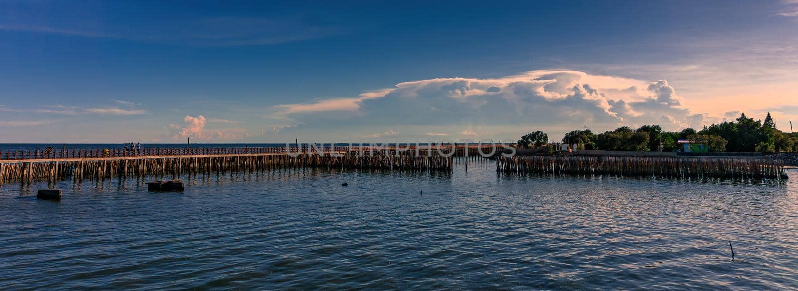 The long red wooden bridge along the sea and the bamboo is coastline protection from sea waves.