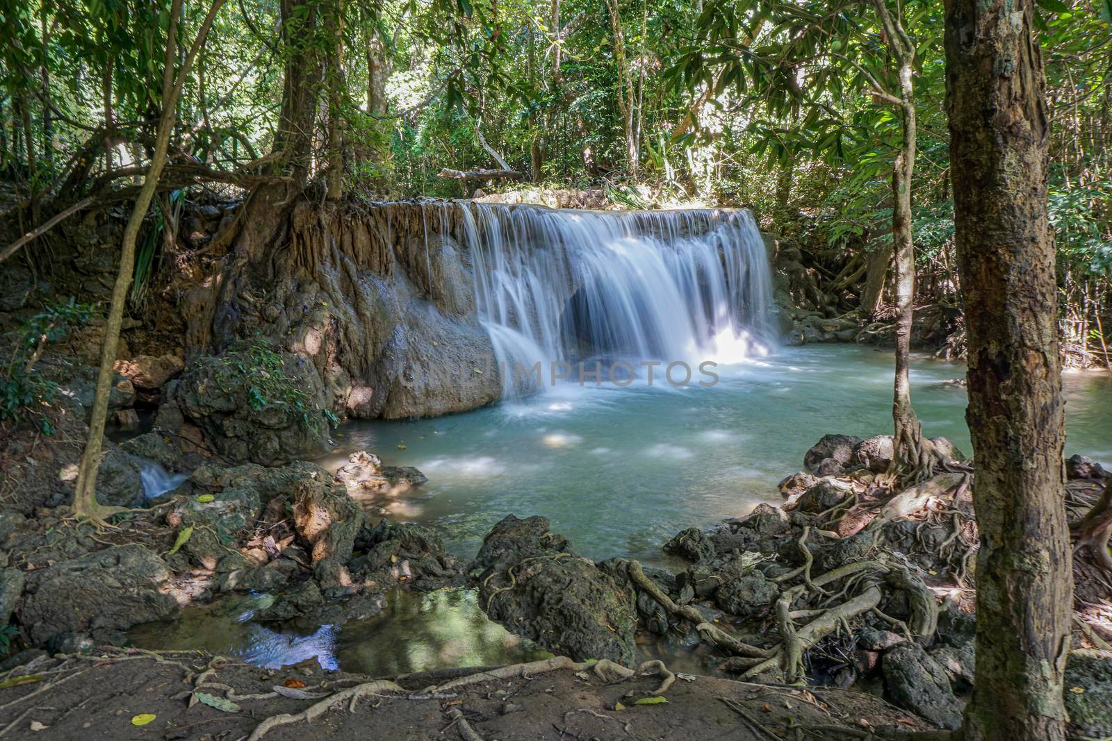 The clean waterfall there is an emerald green colour caused by reflections from trees and lichen circulating through the yellow limestone. Huai Mae Khamin Waterfall, Kanchanaburi Province