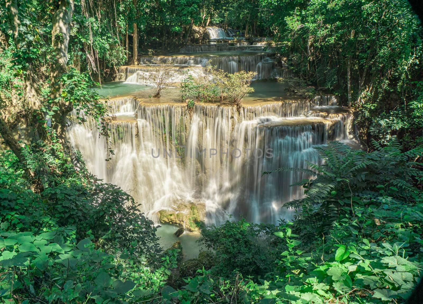 Many waterfalls flow in the frame of plants and green trees. Huai Mae Kamin Waterfall Viewpoint, Kanchanaburi Province