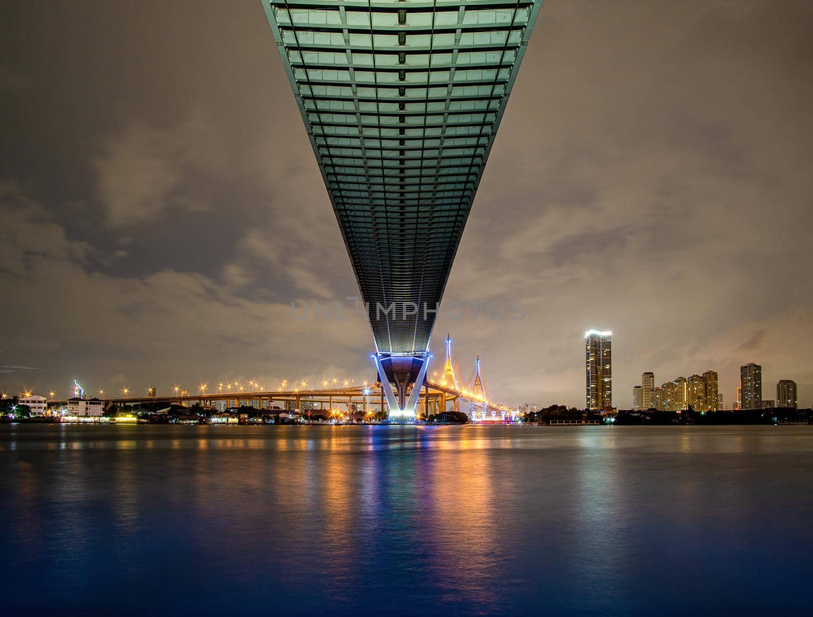 Green led light under the bridge over the river On a cloudy day in the sky. Bhumibol Bridge, Samut Prakan, Thailand