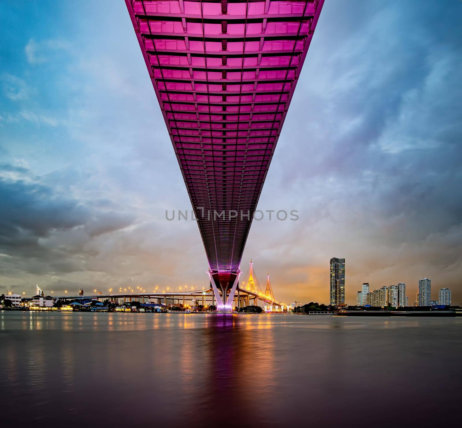 Purple led light under the bridge over the river On a cloudy day in the sky. Bhumibol Bridge, Samut Prakan, Thailand