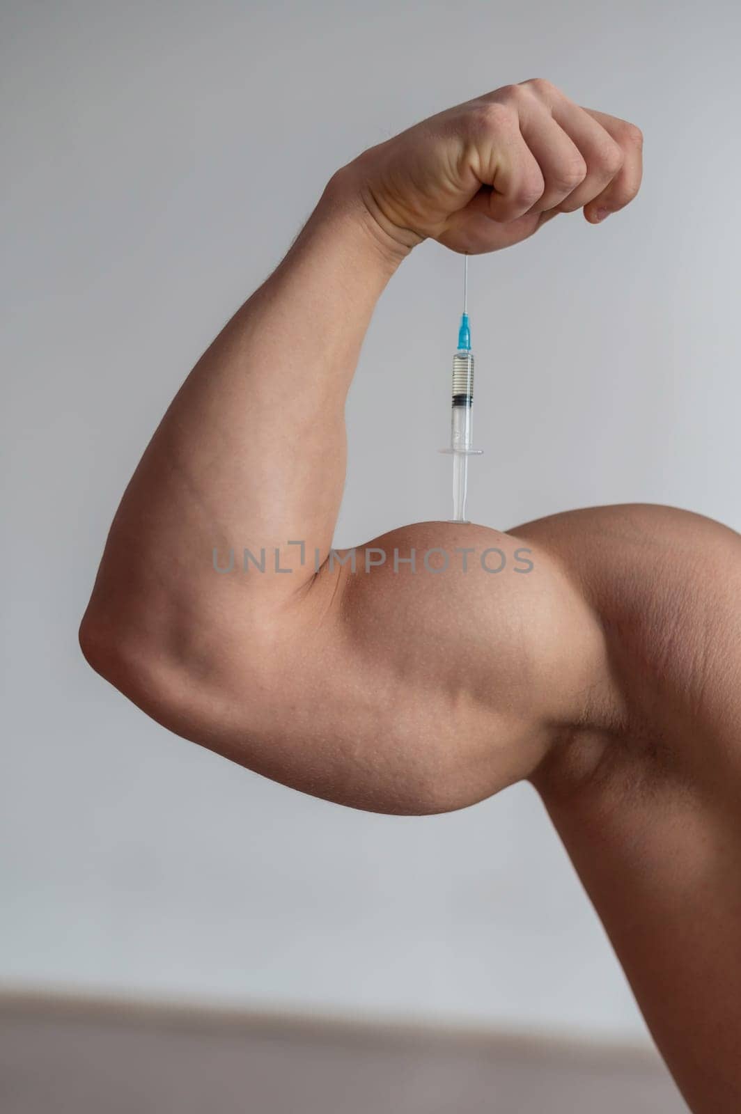 Close-up of male biceps. Unrecognizable male bodybuilder puts himself an injection of testosterone. Faceless athlete takes growth hormone. Vertical . by mrwed54