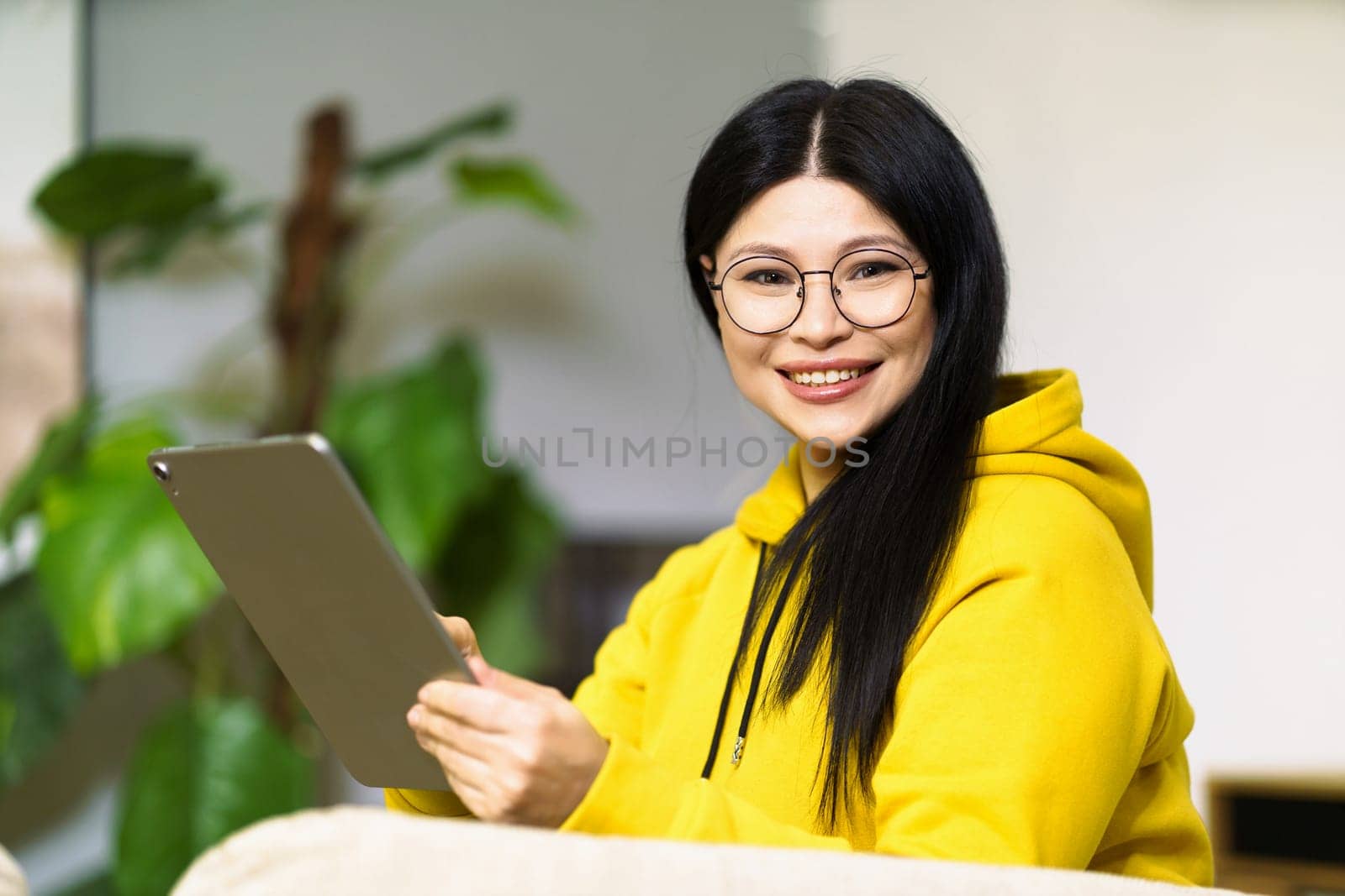 Asian girl in glasses, successfully leading her business from home, using online communication tools and modern gadgets. Concepts of entrepreneurship, innovation, and productivity, highlighting opportunities and challenges of digital future. by LipikStockMedia