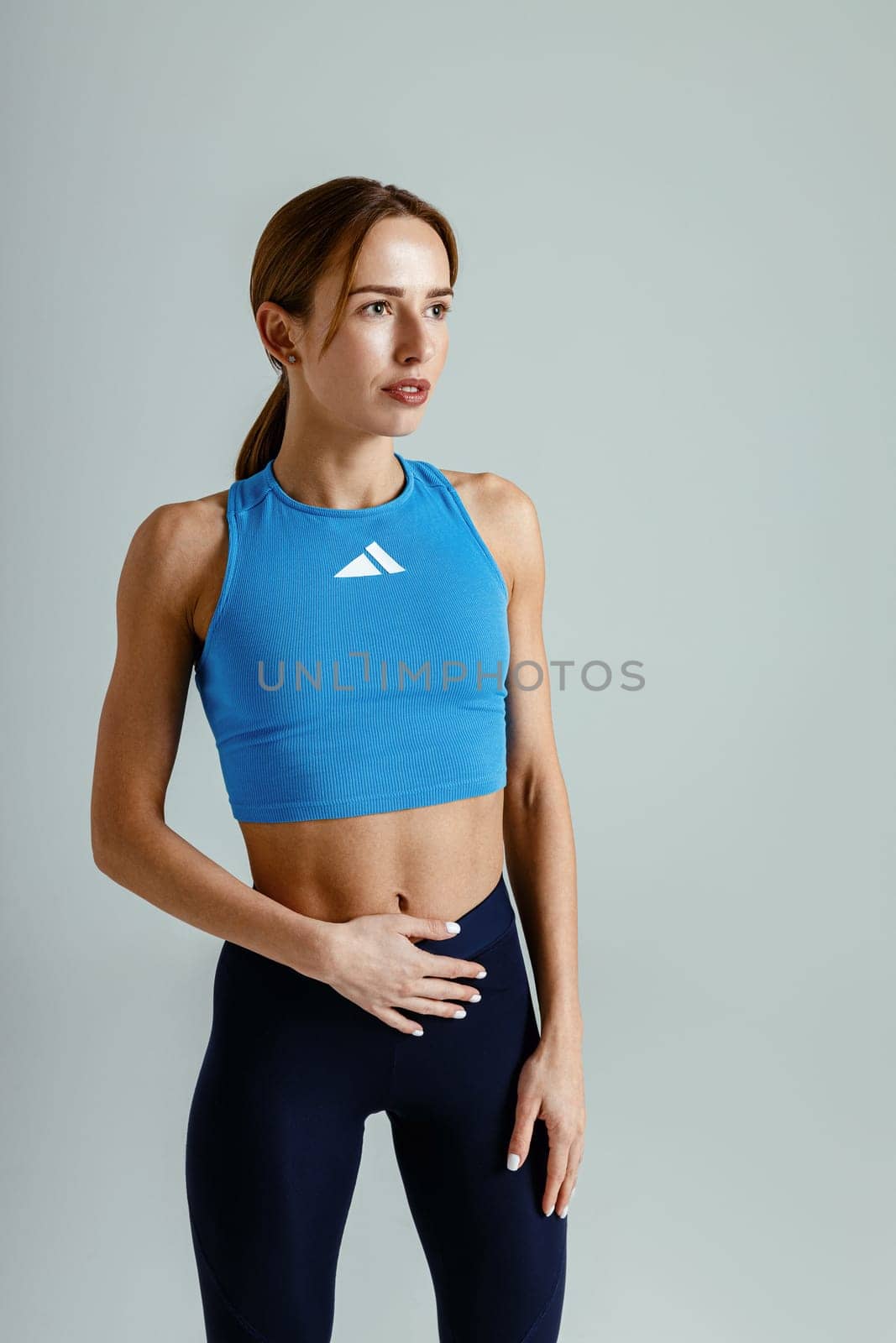 Attractive fitness woman wearing sportswear looking at side on studio background. High quality photo
