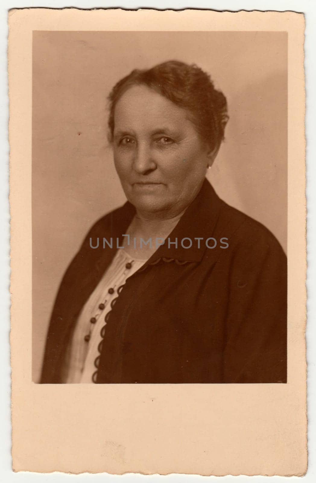 GERMANY - CIRCA 1950s: Vintage photo shows an elderly woman with short hair. Retro black and white studio photography with sepia effect. Circa 1950s.