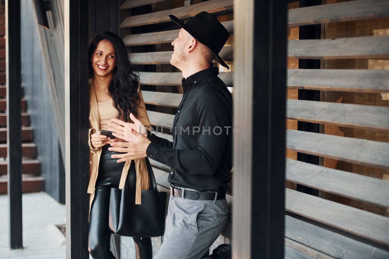 Woman with black curly hair and her man standing together near wooden windows by Standret