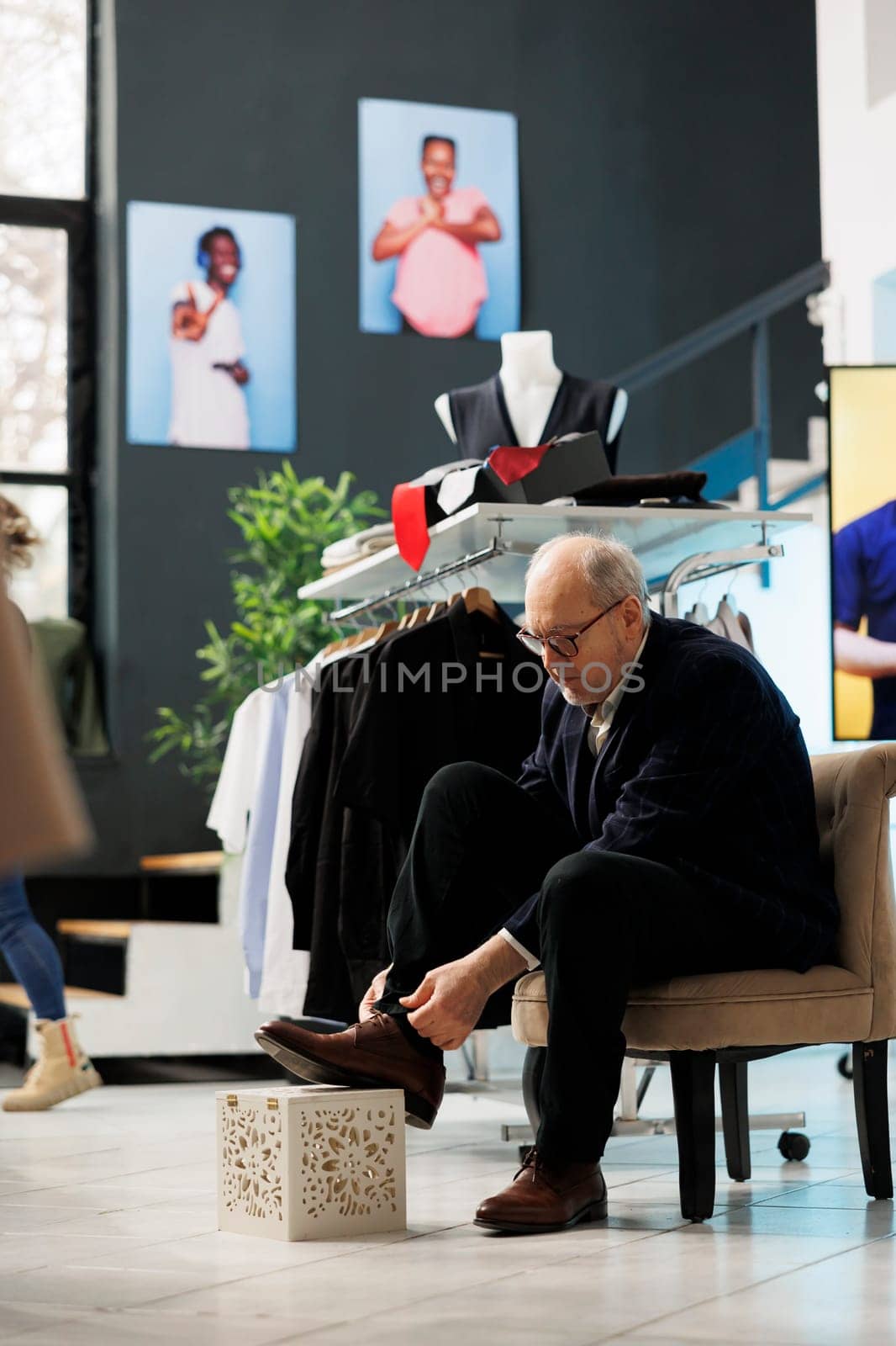 Senior customer trying elegant shoes in modern boutique, shopping for fashionable clothes and accessories. Elderly stylish man buying new collection in clothing store. Fashion concept