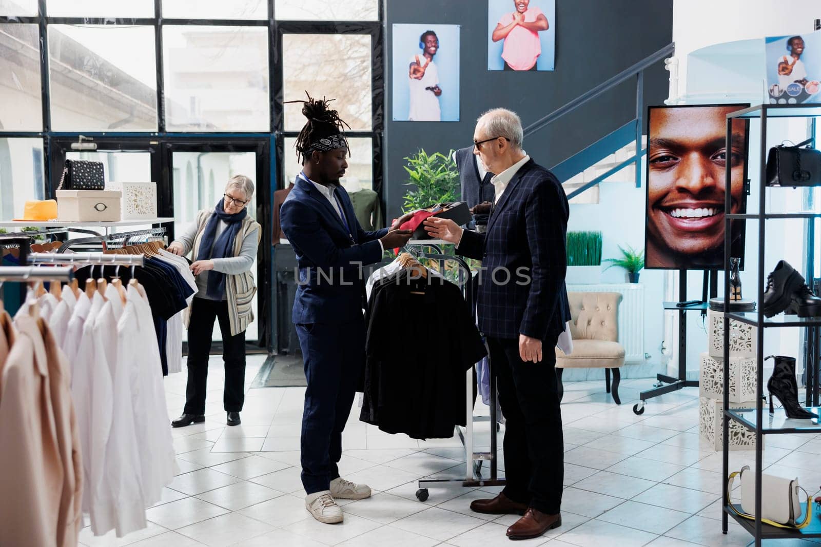 Stylish worker helping senior client with red tie by DCStudio