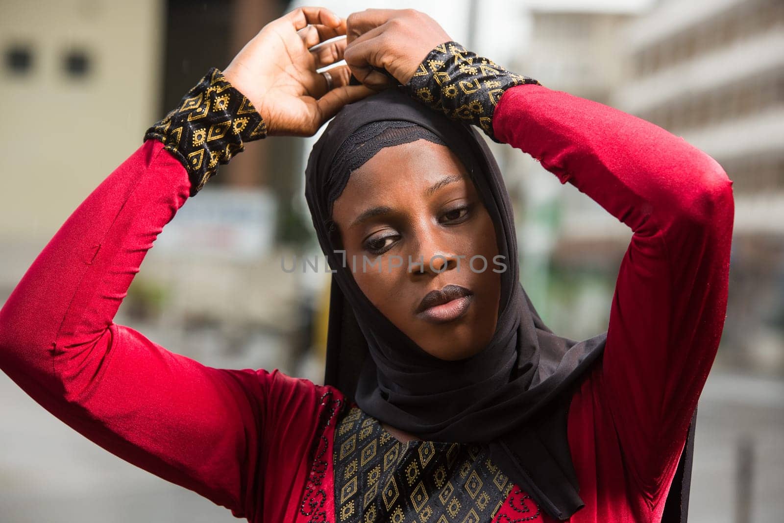 young muslim woman standing outdoors adjusting her veil.