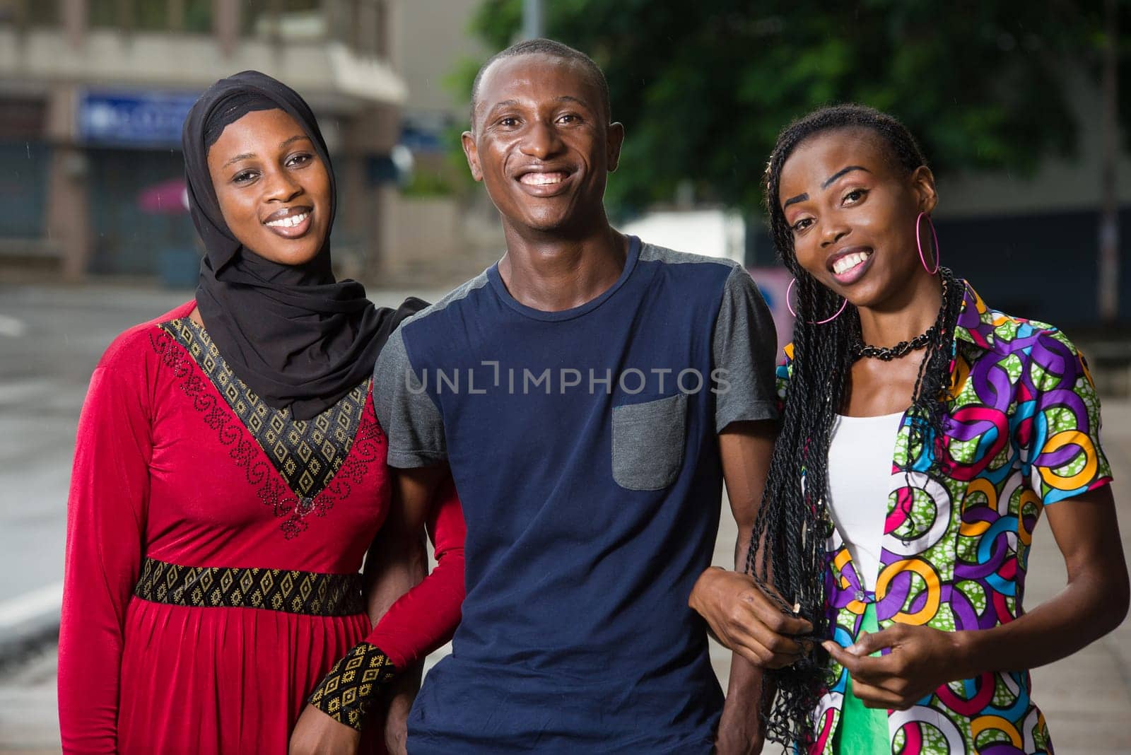 group of young people standing outdoors looking at camera laughing.