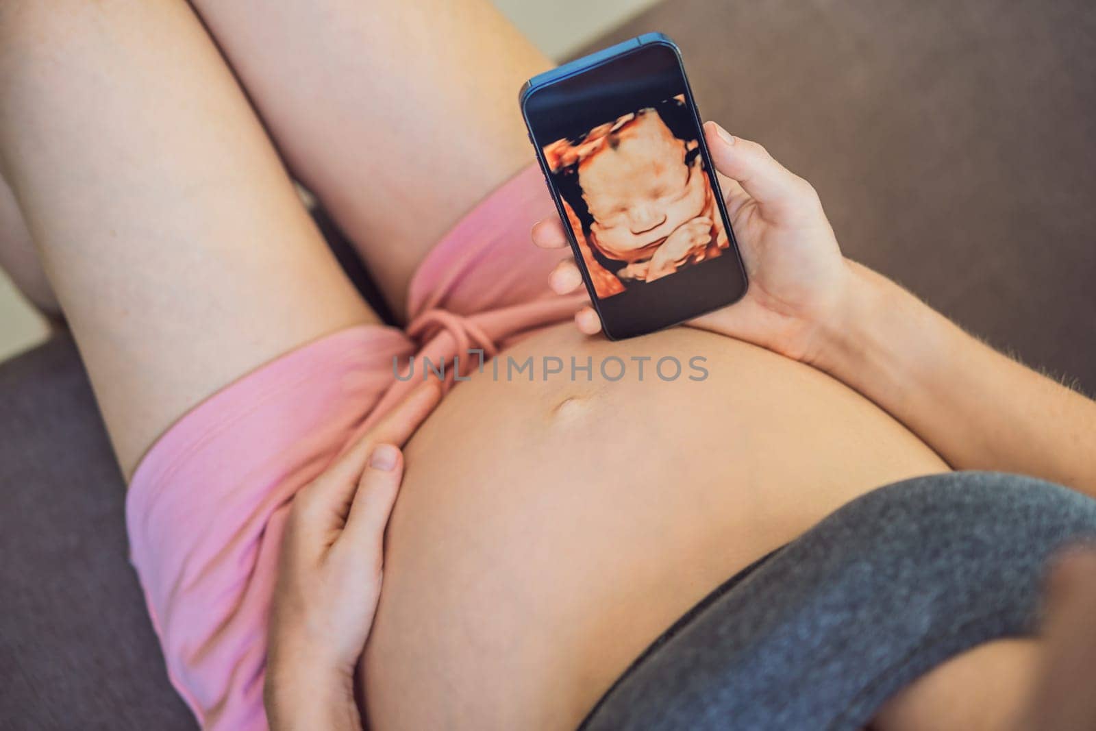 Pregnant woman holding and showing mobile phone with fetal ultrasound photo by galitskaya