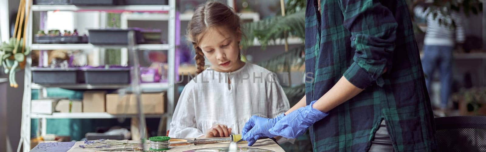 Flourist shop with different kinds of dryed flowers. Young happy confident specialist is working with her female kid. by Yaroslav_astakhov