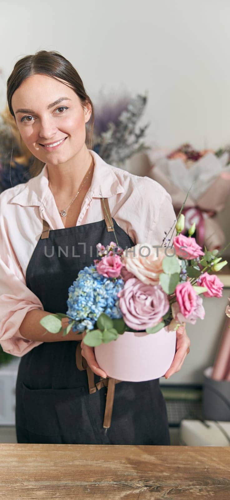 Professional florist young woman is doing bouquets at flower shop by Yaroslav_astakhov