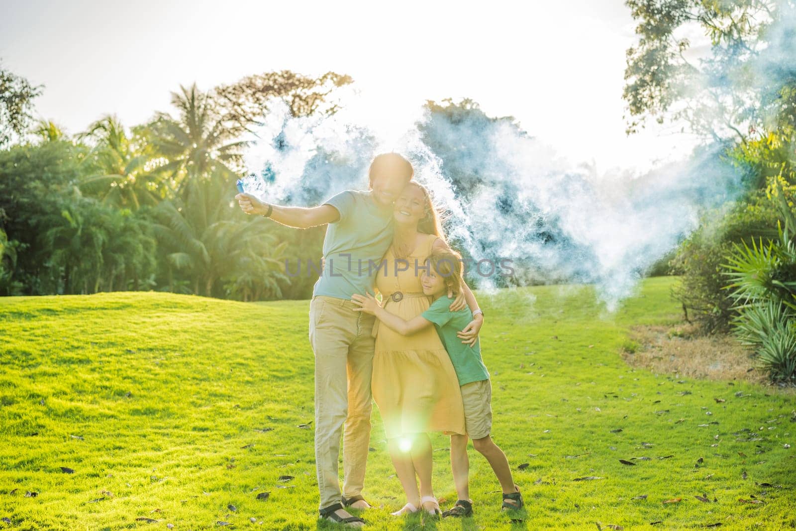 Pregnant mom, dad and son at the gender party on the golf course release blue smoke. Gender reveal announcement on the golf course. Loving family expecting baby boy. Happy moments.