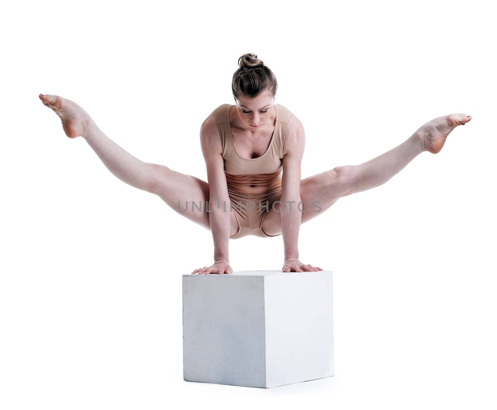 Young pretty acrobat posing with cube in studio, isolated on white