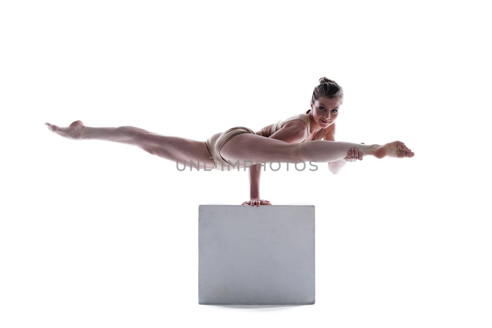 Attractive gymnast doing exercises on cube in studio
