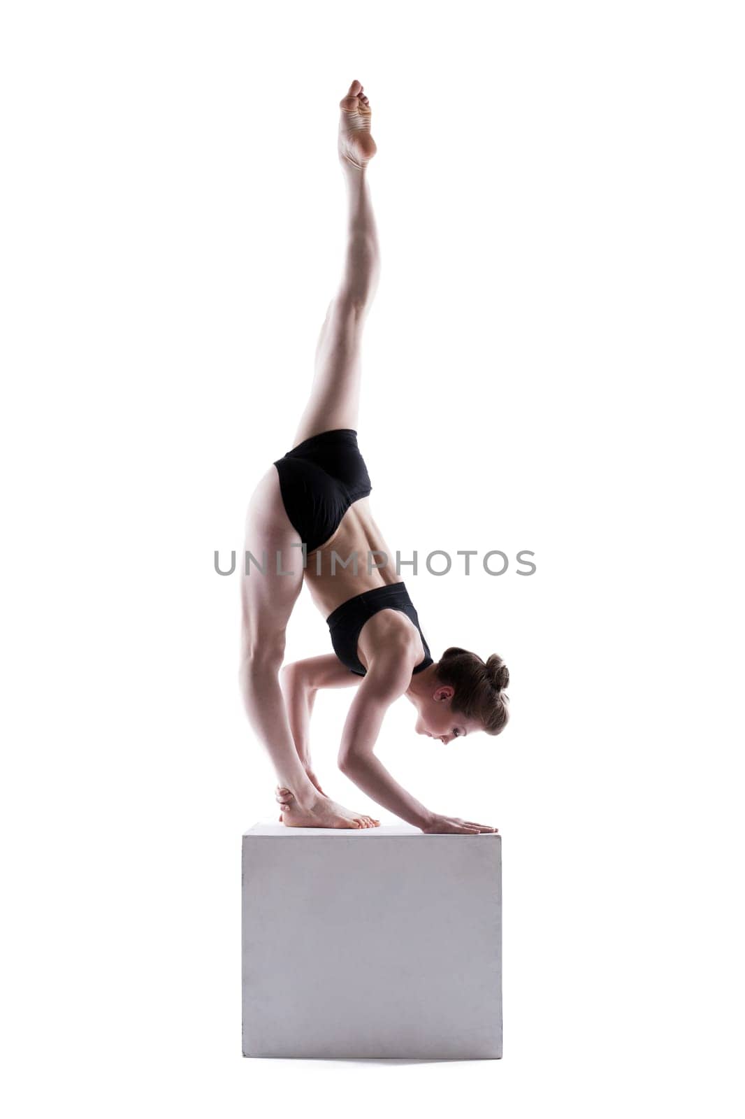 Beautiful girl posing doing exercises on cube, isolated on white