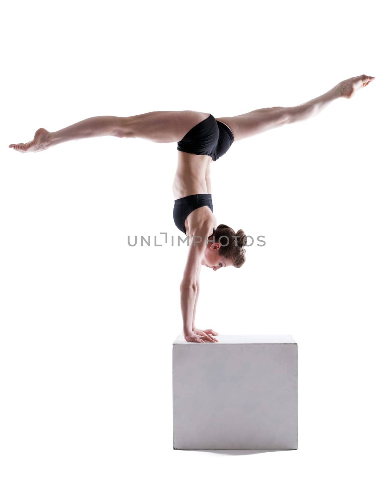 Flexible gymnast balancing on cube in studio, isolated over white background
