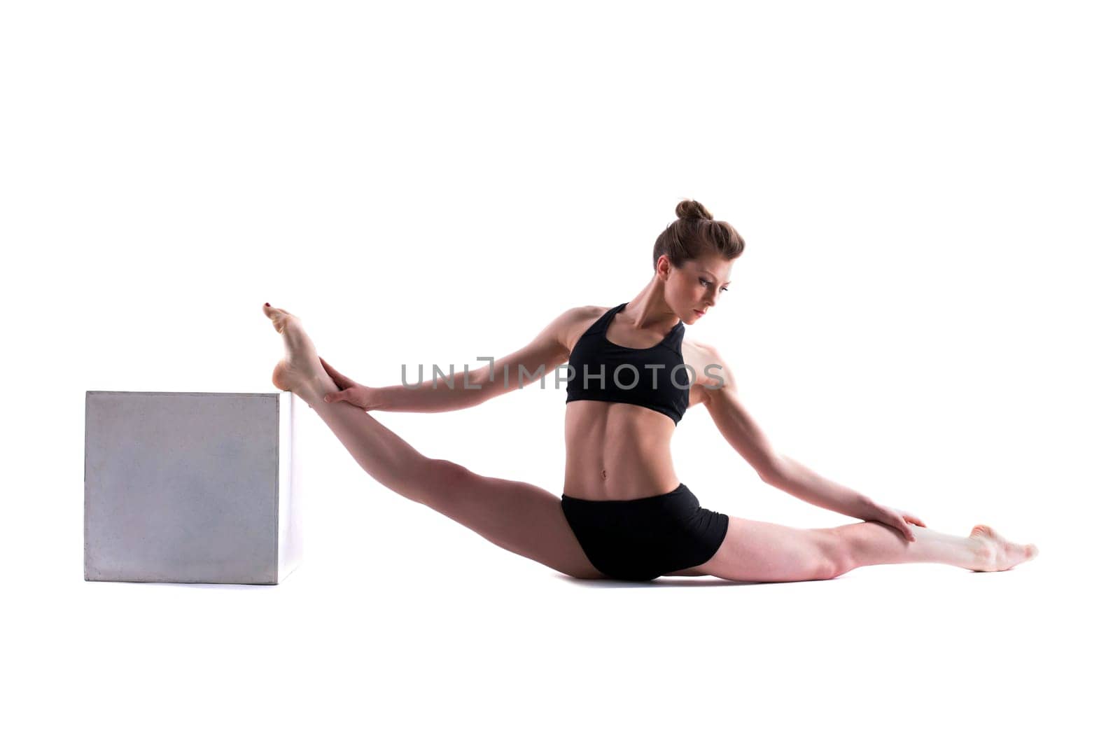 Attractive gymnast posing with cube in studio, isolated on white