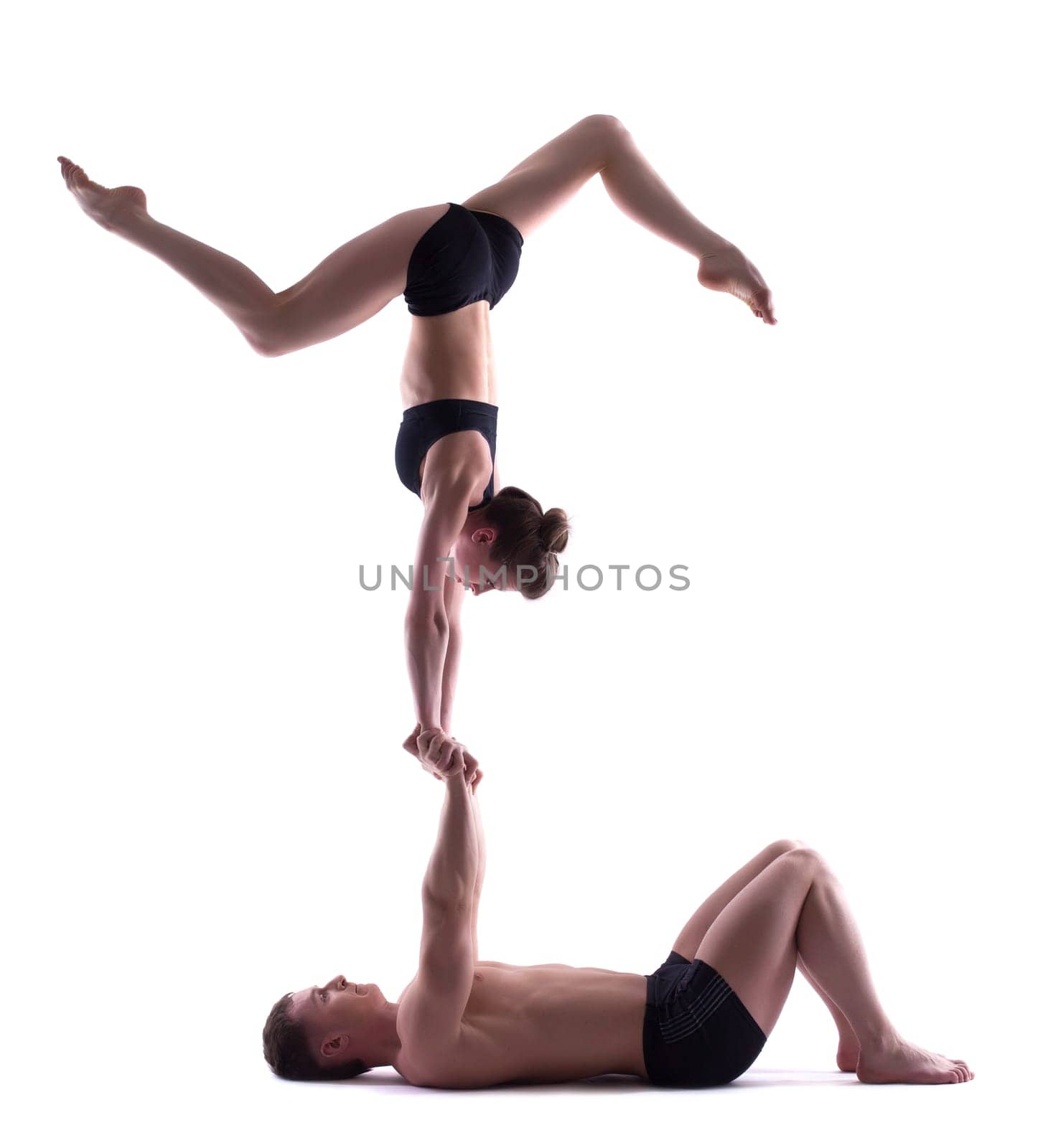 Two young attractive acrobats posing in studio, isolated on white